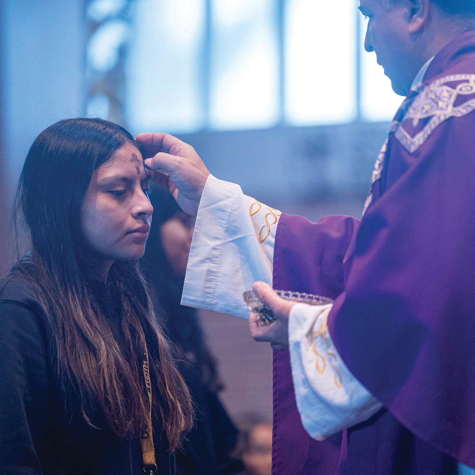 During an Ash Wednesday Mass on Feb. 18 at Our Lady of Sorrows Church in Takoma Park for students from Don Bosco Cristo Rey High School, Washington Auxiliary Bishop Evelio Menjivar places ashes on the forehead of student Melanie Luna. (Catholic Standard photo by Mihoko Owada)