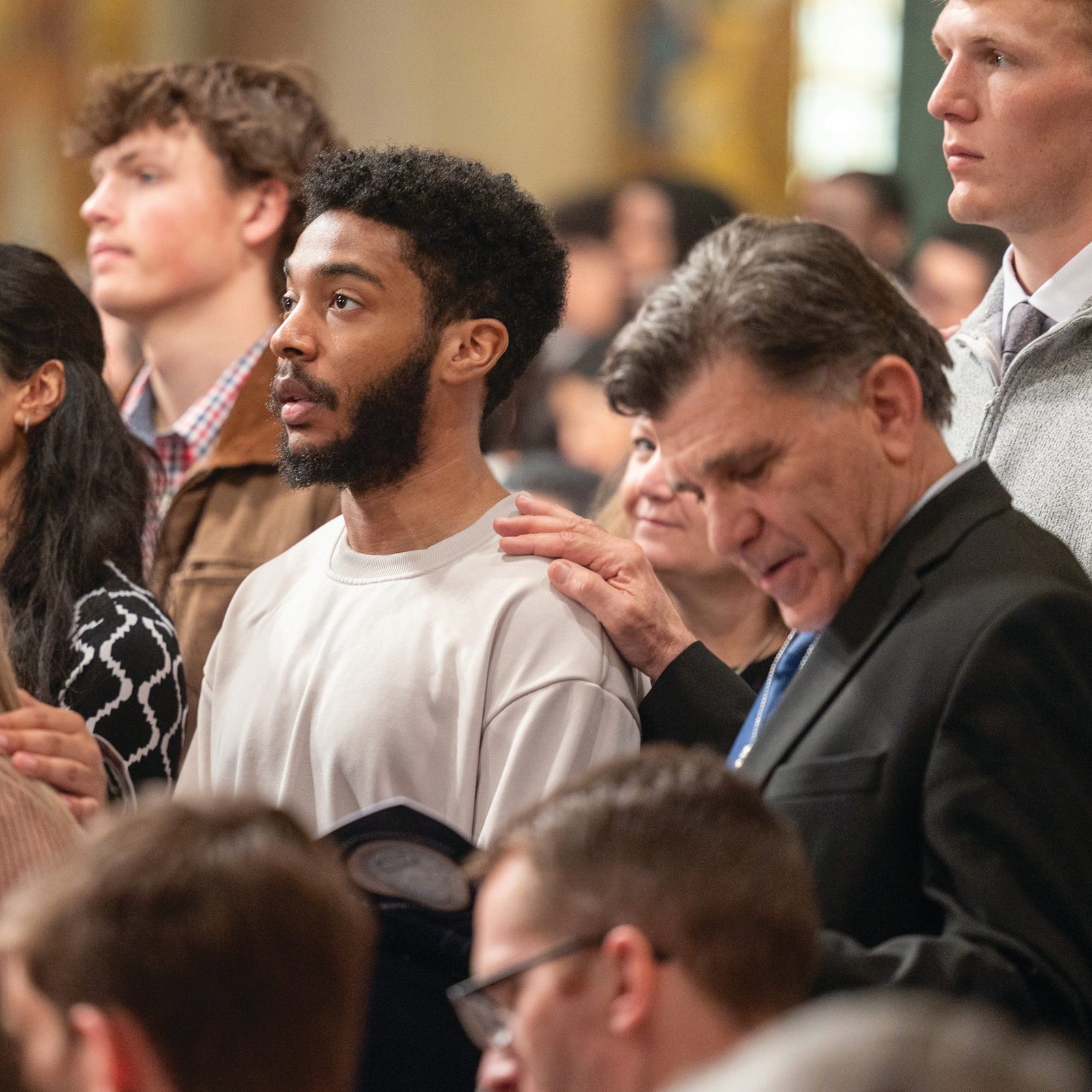 Above and below, sponsors place their hands on the shoulders of candidates during the March 16, 2025 Rite of Election and Call to Continuing Conversion at the Basilica of the National Shrine of the Immaculate Conception. Candidates are already baptized who will receive the sacraments of Confirmation and Communion at the Easter Vigil. (Catholic Standard photos by Mihoko Owada)