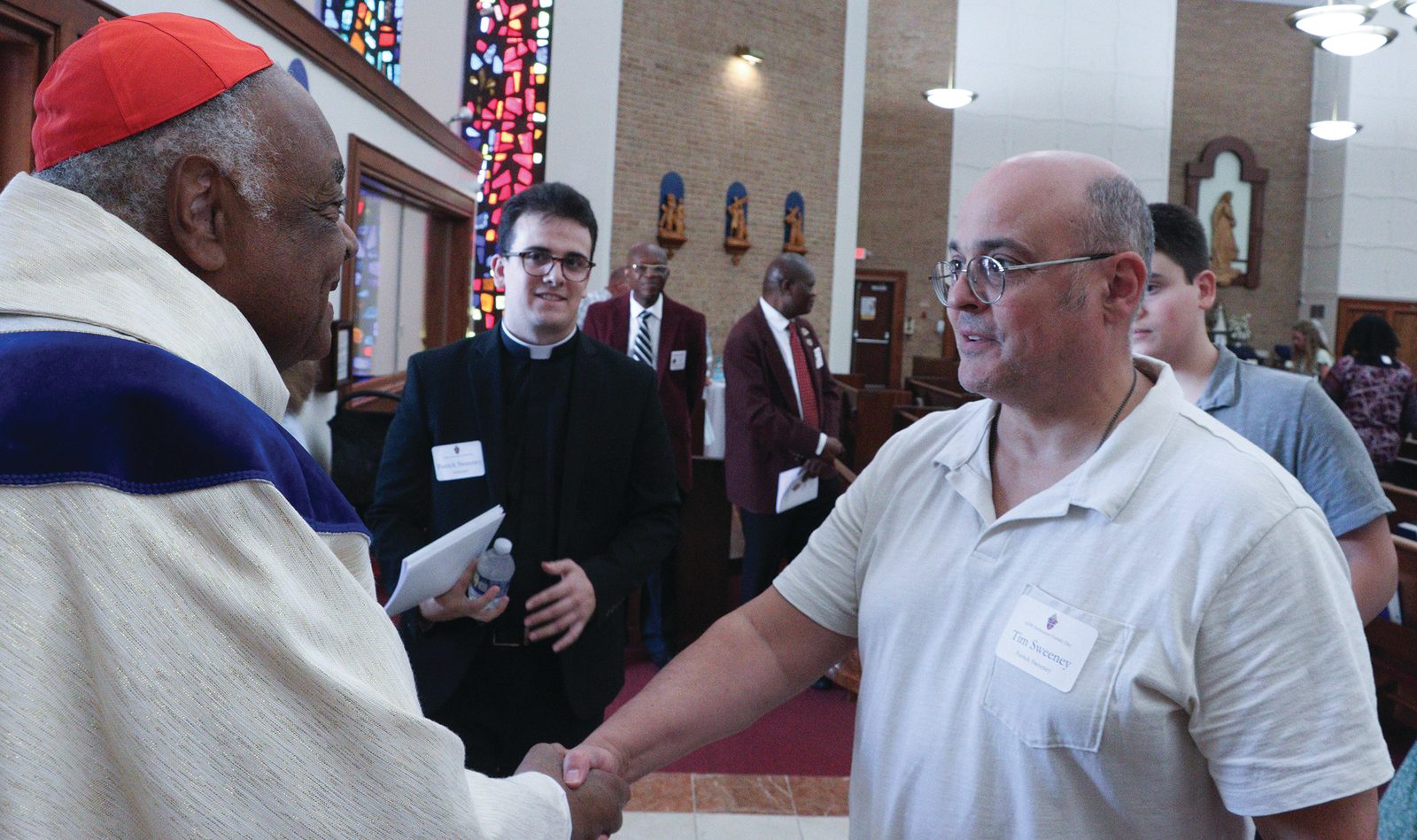 Above, after celebrating the July 27 Seminarian Family Day Mass at St. Mary’s Church in Landover Hills, Cardinal Gregory greets Tim Sweeney (at right), the father of seminarian Patrick Sweeney (at center). Below, the cardinal greets greets Terri Morauer (at left), the mother of seminarian Will Morauer (at center). Standing behind her is the seminarian’s father, David Morauer. The luncheon and a Mass that preceded it were sponsored by The Roman Catholic Archdiocese of Washington. (Catholic Standard photos by Javier Diaz)