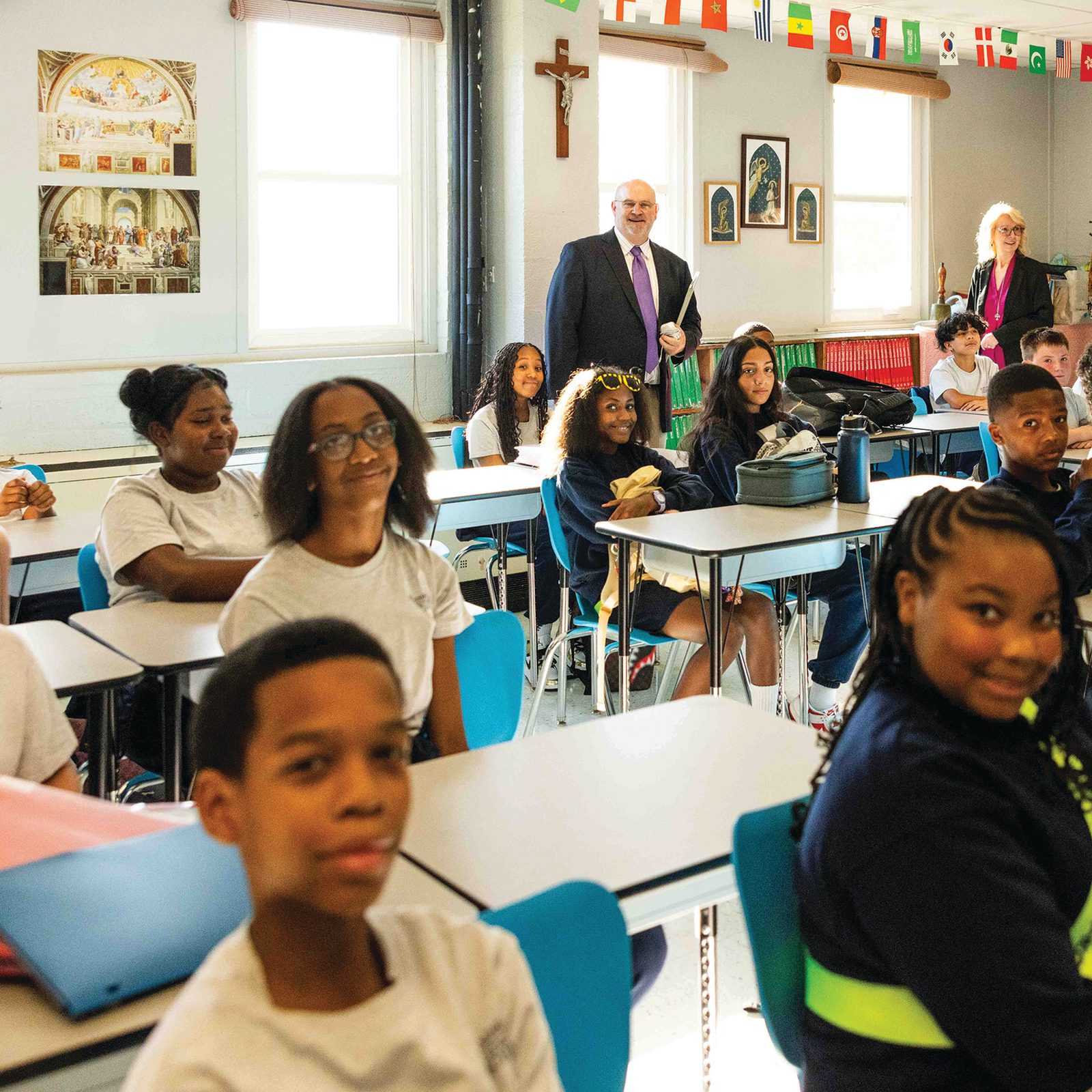In the background, Dr. Philip Robey, the principal at St. Ambrose School in Cheverly, Maryland, and Michelle Truss, the assistant principal at the school, visit the seventh grade class of Jamie Pugliese on the first day of classes, Aug. 26, 2025. (Catholic Standard photo by Andrew Biraj)