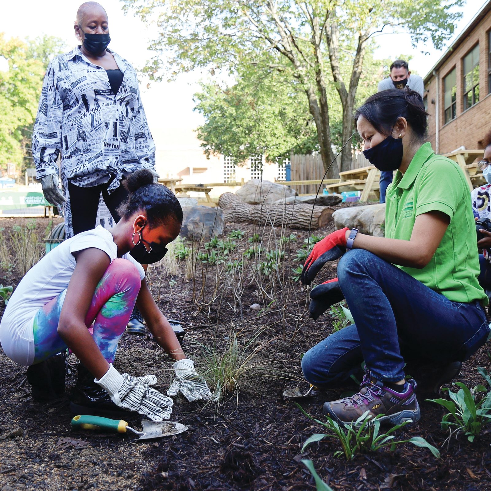 At left, Rylie Jordan, then a fourth grader at St. Thomas More Catholic Academy in Washington, D.C., plants vegetation in the new rain garden behind the school on Oct. 16, 2021. She is joined at right by Trinh Doan, a watershed protection specialist with the District of Columbia’s Department of Energy & Environment who manages the RiverSmart Schools program. (Photo by Gaillard Stohlman for The Roman Catholic Archdiocese of Washington)