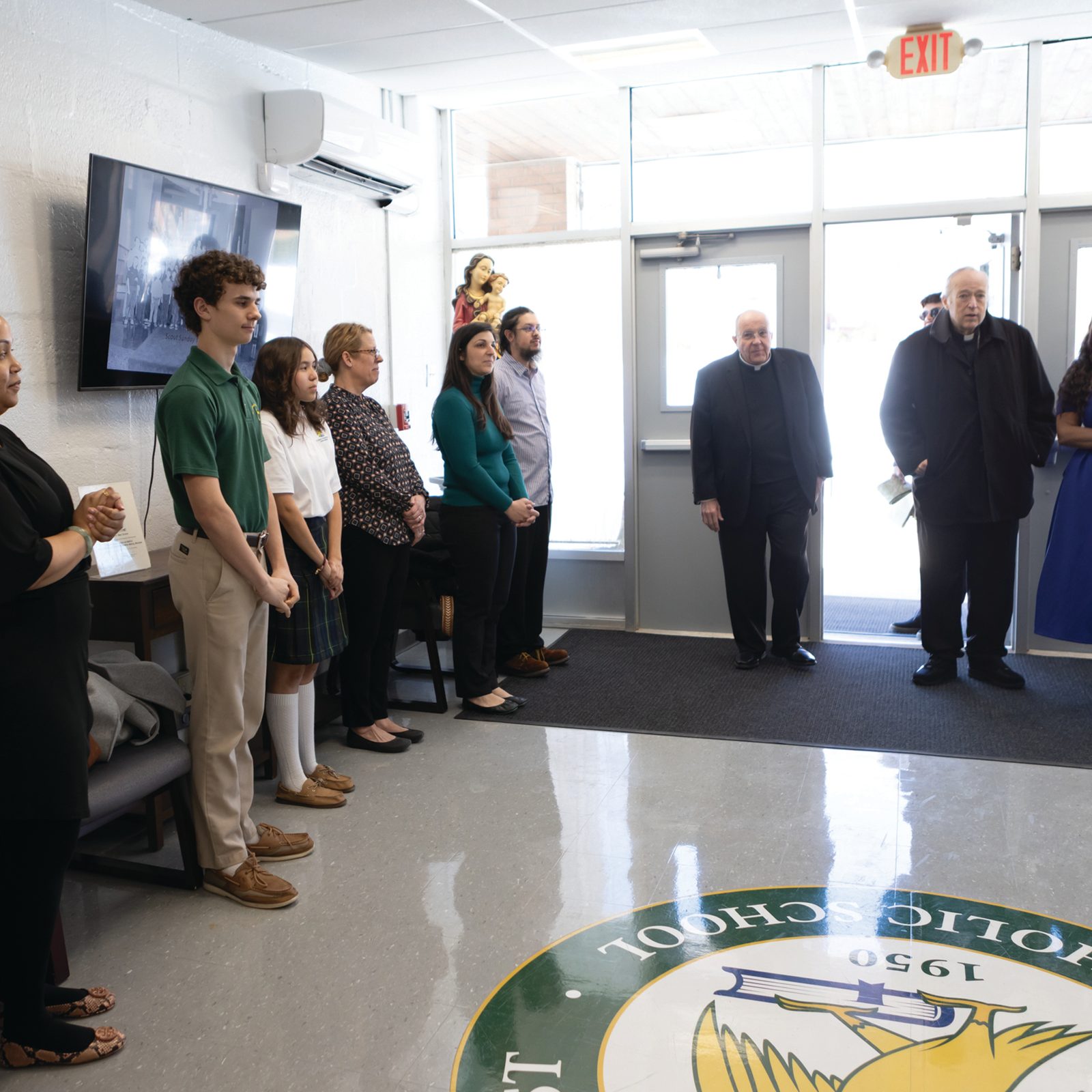 Members of the School Advisory Board, representatives of the Home and School Association and student ambassadors line up to greet Cardinal Robert W. McElroy as he visits St. John the Evangelist School in Silver Spring Feb. 13 after celebrating a Mass for students. To the left of the cardinal is Father Joseph Calis, pastor of the St. John the Evangelist Parish, and at right of the cardinal is Shindana Crawford, principal of St. John the Evangelist School. (Catholic Standard photo by Rachael Lincoln)