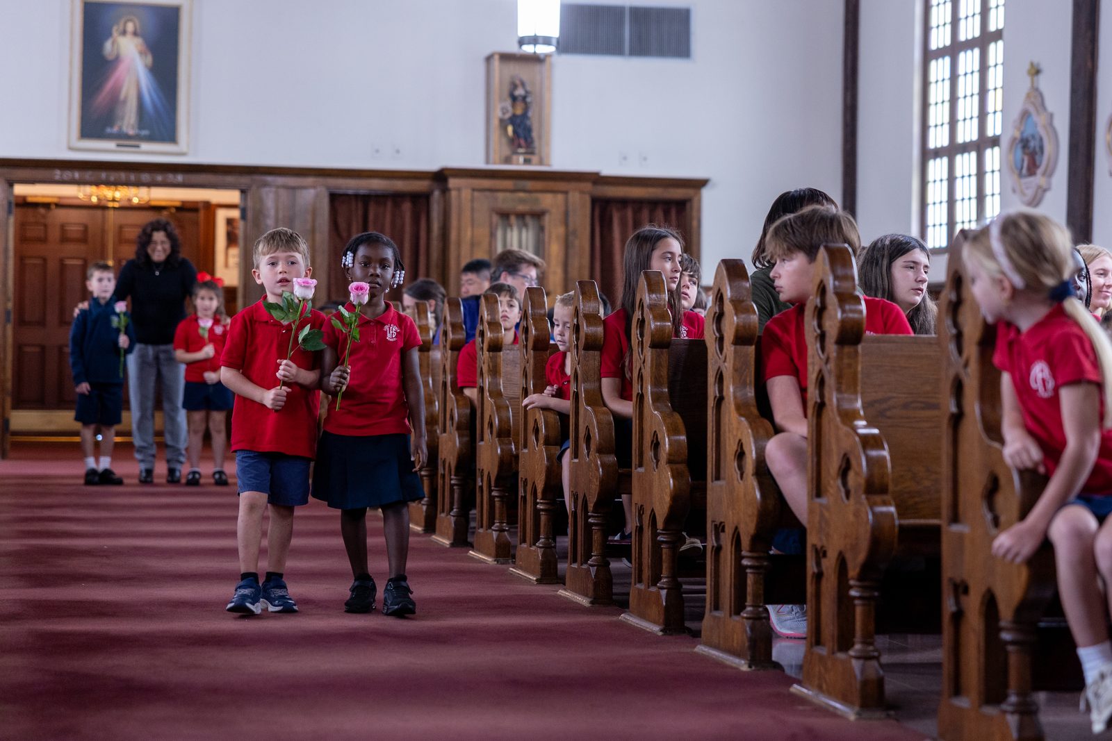 Lucas Tweedale and Marvert Atabongafac, who are kindergarten students at Little Flower School in Great Mills, Maryland, bring roses to the altar during a Mass on Oct. 1, 2024 at Holy Face Church in Great Mills for the feast day of the school’s patron saint, St. Thérѐse of Lisieux, who is known as the Little Flower. (Catholic Standard photo by Mihoko Owada)