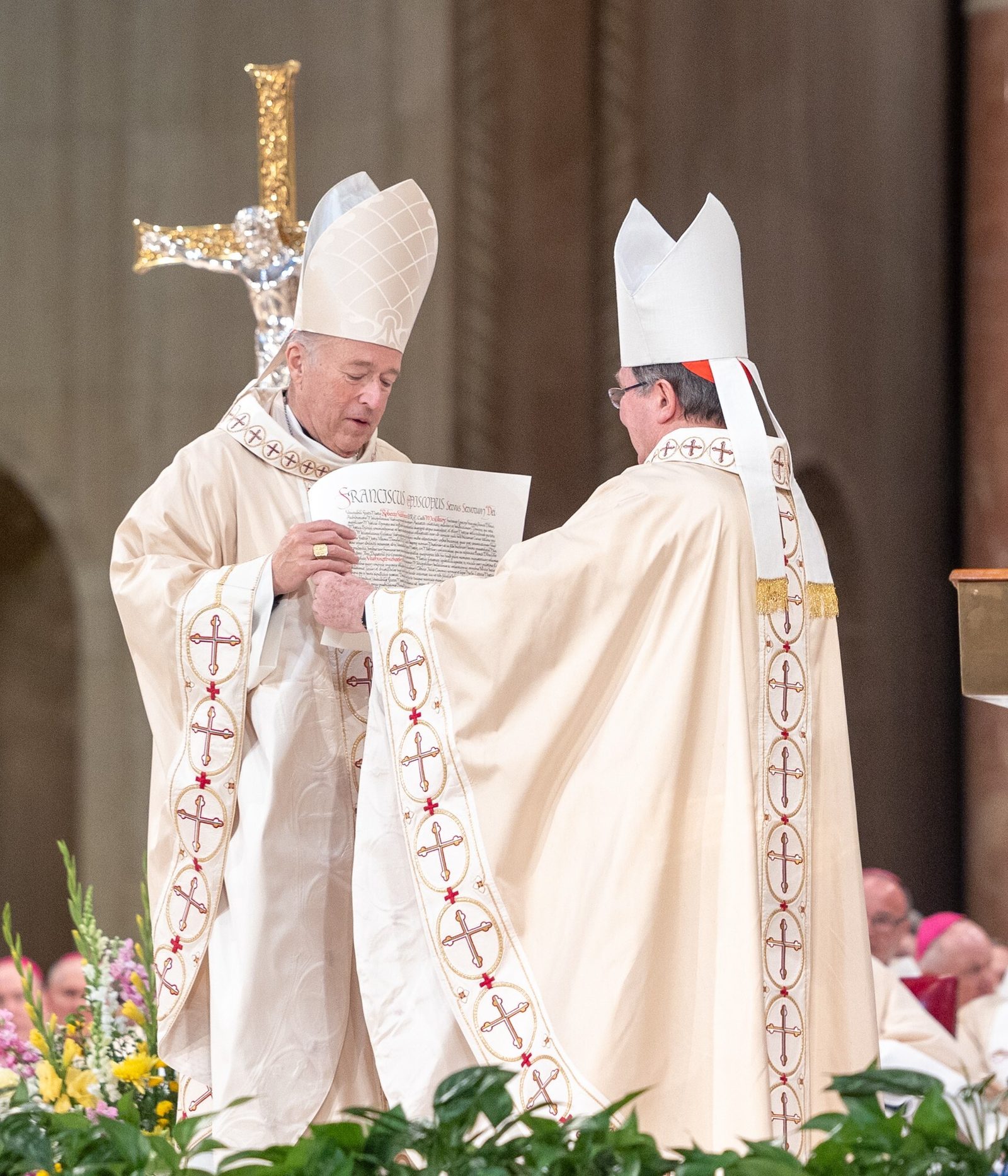 After reading the apostolic mandate from Pope Francis appointing Cardinal Robert McElroy as the new archbishop of Washington during a Solemn Mass of Installation on March 11, 2025 at the Basilica of the National Shrine of the Immaculate Conception, Cardinal Christophe Pierre, at right, the apostolic nuncio to the United States, hands the mandate to Cardinal McElroy, at left. (Catholic Standard photo by Mihoko Owada)