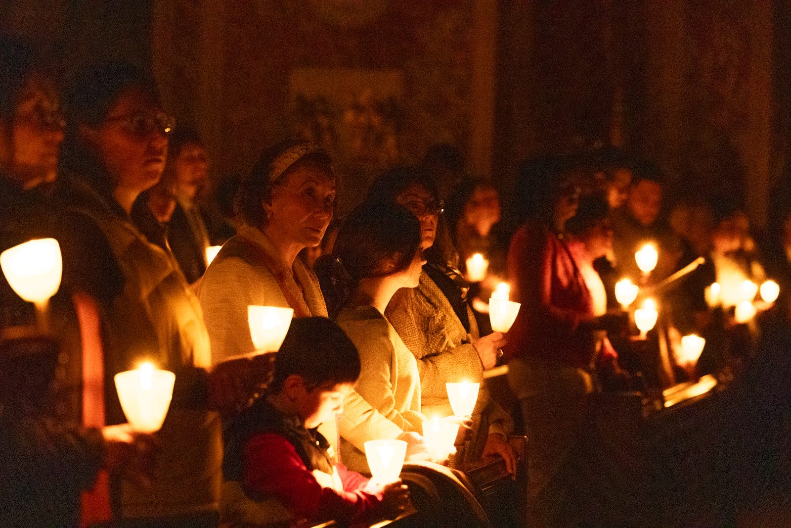 People hold candles in the darkened Cathedral of St. Matthew the Apostle in Washington, D.C., during the beginning of the March 30, 2024 Easter Vigil there. (Catholic Standard photo by Mihoko Owada)