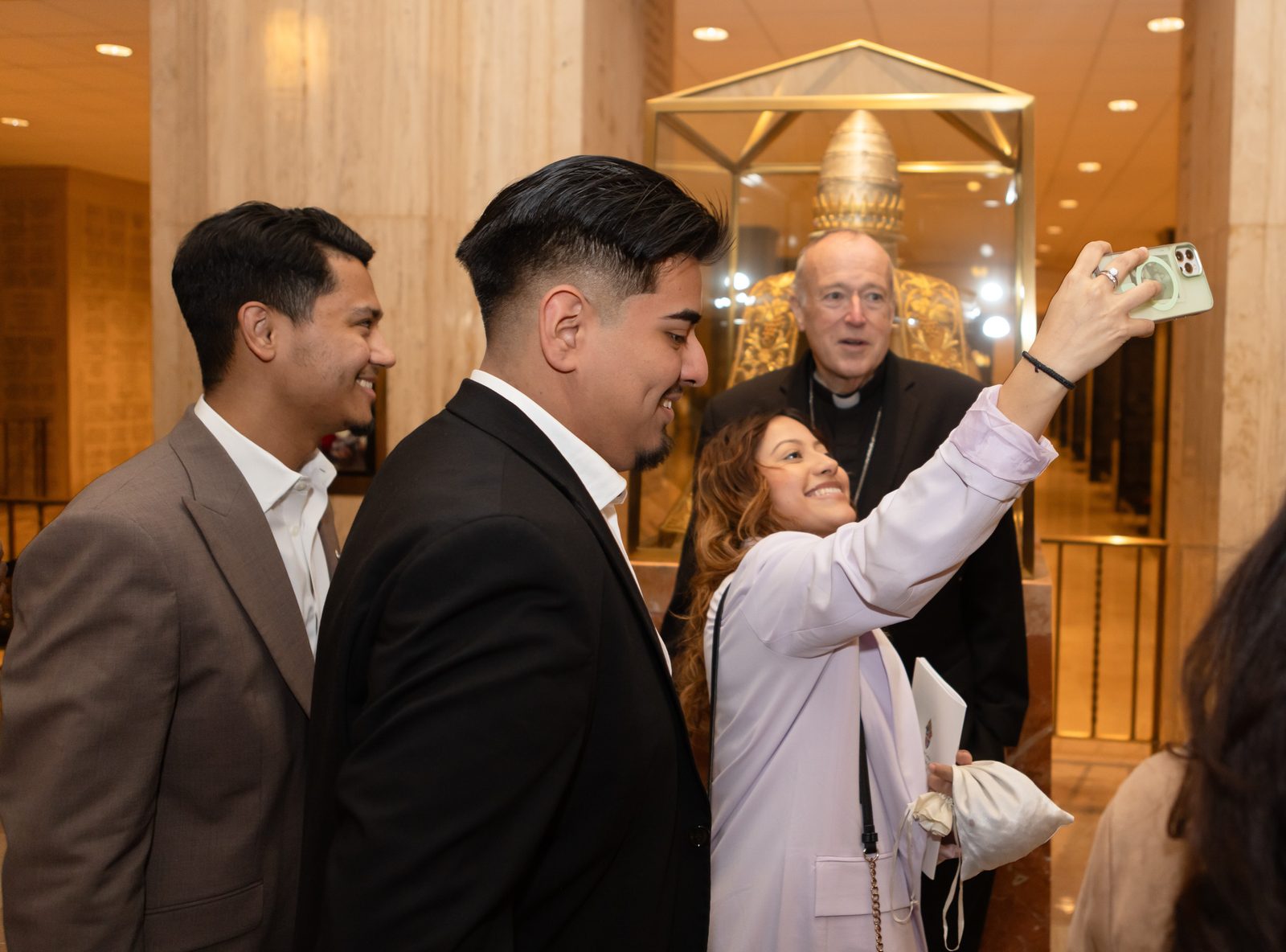A young woman takes a selfie with Cardinal Robert McElroy, the new archbishop of Washington, as he met with people after his Mass of Installation on March 11, 2025 at the Basilica of the National Shrine of the Immaculate Conception. (Catholic Standard photo by Rachel Lincoln)