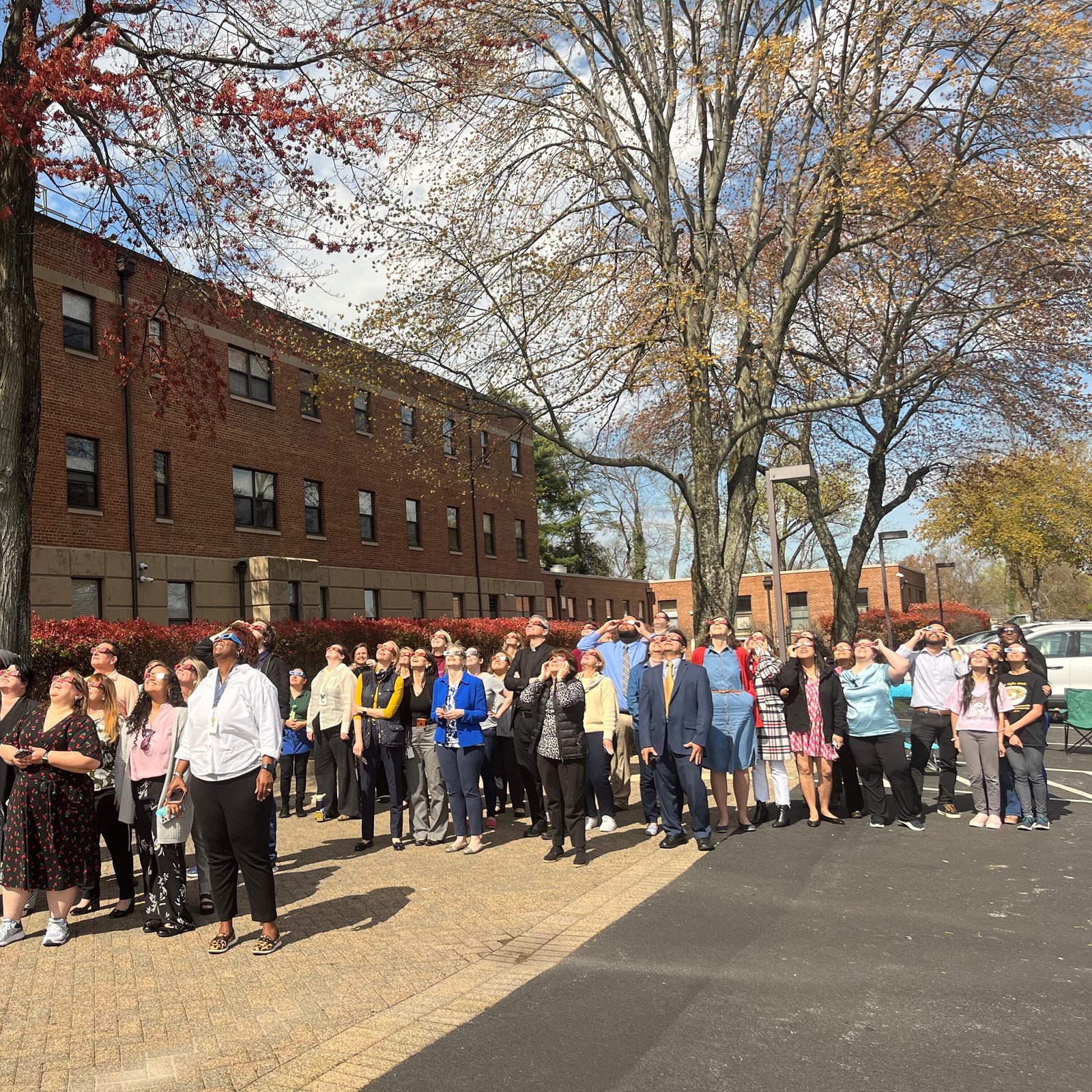 About 60 employees of The Roman Catholic Archdiocese of Washington and guests gathered outside the Archdiocesan Pastoral Center in Hyattsville, Maryland, on April 8, 2024 to view the solar eclipse. Refreshments provided by the archdiocese’s Human Resources Department and Catholic Schools Office included Sun Chips, Moon Pies and Sunkist soda. (Catholic Standard photo by Mark Zimmermann)