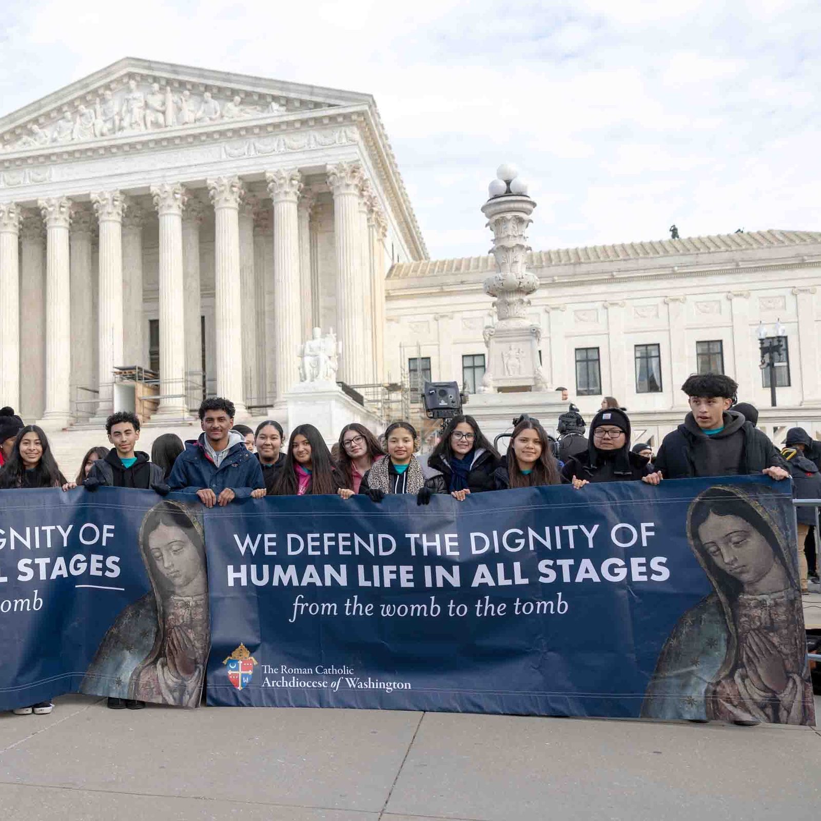 Acompañados por el obispo auxiliar de Washington, Evelio Menjívar (primero de la izq.), jóvenes hispanos católicos posan frente a la Corte Suprema de Justicia portando su consigna en una gran pancarta que reza: “Defendemos la dignidad de la vida humana en todas sus etapas”, luego de caminar en la Marcha por la Vida, el  23 de enero de 2026.